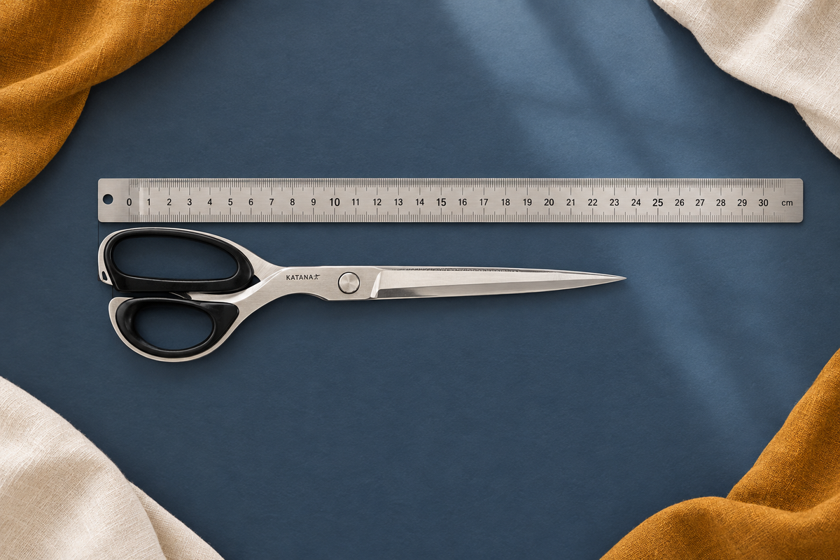 Ciseaux de couture Katana 25 cm parallèles à une règle de 30 cm sur une table bleu ardoise
